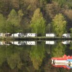 Camping Clausensee Blick vom See auf den Wohnwagen und Zeltstellplatz und Mobilheime vom Campingplatz 150x150