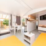 Camping Landal Sonnenberg Wohnbereich mit Fernseher Kueche und Esstisch mit Zugang zur Veranda im Mobilheim vom Campingplatz 150x150
