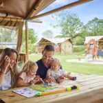 Camping TerSpegelt Gaeste sitzen vor dem Glampingzelt im Schatten der Baeume auf dem Campingplatz 150x150
