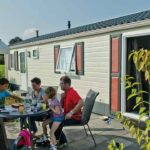 Campingpark Kerstgenshof Familie am Esstisch auf der Veranda vom Mobilheim auf dem Campingplatz 150x150