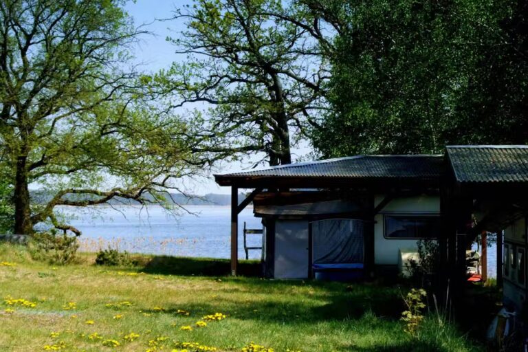 FKK Ferienidyll am Raetzsee Stellplatz im Schatten unter Baeumen mit Seeblick auf dem Campingplatz 768x512