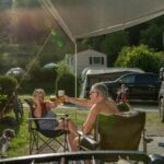 Family Resort Kleinenzhof Campingplatzgaeste stossen neben dem Wohnmobil an 150x150