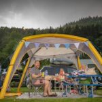Family Resort Kleinenzhof Gaeste des Campingplatzes die am Tisch unter einem Zelt sitzen 150x150