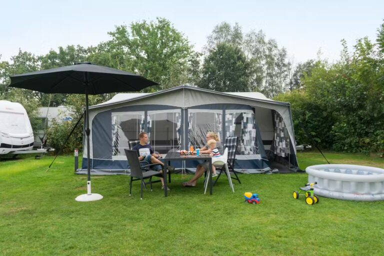 Kampeerdorp De Zandstuve Gaeaste vor ihrem Wohnwagen in der Sonne 768x513