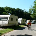 Naturcamping ckeritz Camper mit Fahrrad entlang der Wohnwagen und Wohnmobile auf dem Campingplatz 150x150