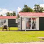 Ostseecamping Familie Heide auf einer Wiese gelegene moderne Mietunterkuenfte mit grosser Fensterfront und einer gepflasterten Terrasse mit Stuehlen und einem Tisch 4c807455 014a 4b77 986b f2bbc9ba624d 150x150