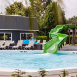 Familiecamping De Belten Pool mit Rutsche Liegestuehlen und Sonnenschirmen auf dem Campingplatz 150x150