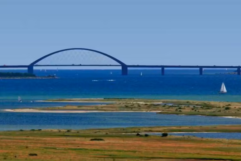 Camping Fluegger Strand Strand in der Naehe des Campingplatzes mit Bruecke in der Ferne  768x512