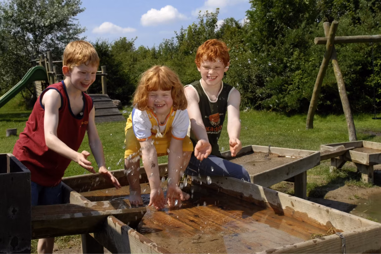 Camping Suedstrand Kinder beim Wasserspiel im Gruenen auf dem Campingplatz 1224x816