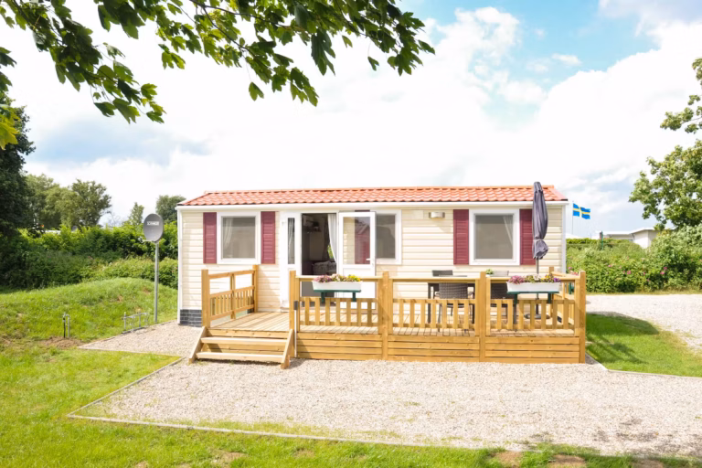 Ostsee Freizeitpark Booknis Blick auf Mobilheim mit Veranda auf dem sonnigen Gelaende vom Campingplatz 768x512
