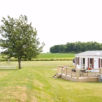 Ostsee Freizeitpark Booknis Mobilheim mit Veranda mit Blick auf die gruenen Felder auf dem Campingplatz 150x150